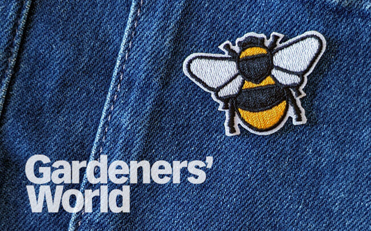 Iron on bee patch on blue denim overalls with Gardeners World logo