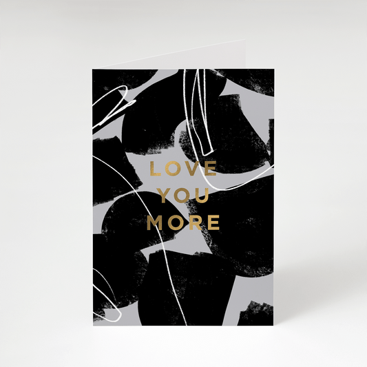 Stylish Love Card reads ' Love You More' in a bold font, printed in gold foil on an abstract grey and black background
