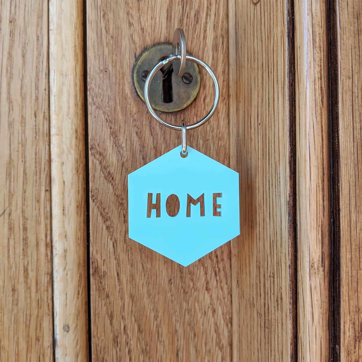 Mint green hexagonal 'HOME' keyring on a wooden door